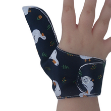 Load image into Gallery viewer, Image showing a button fastening on a White ducks on a dark background-themed thumb guard to help stop thumb sucking and other habits. Has a moisture resistant lining. The Thumb Guard Store.
