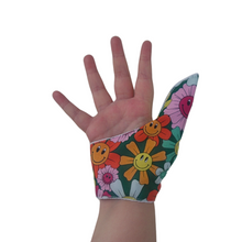 Load image into Gallery viewer, A fabric thumb guard made by The Thumb Guard Store, designed to help children and adults stop habits such as thumb sucking and skin picking. The guard in the image has a smiling flower-themed outer fabric on a green background
