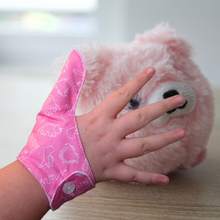 Load image into Gallery viewer, Pink coloured thumb guard with a dinosaur design. Moisture resistant lining, to help stop thumb sucking. Made by The Thumb Guard Store.
